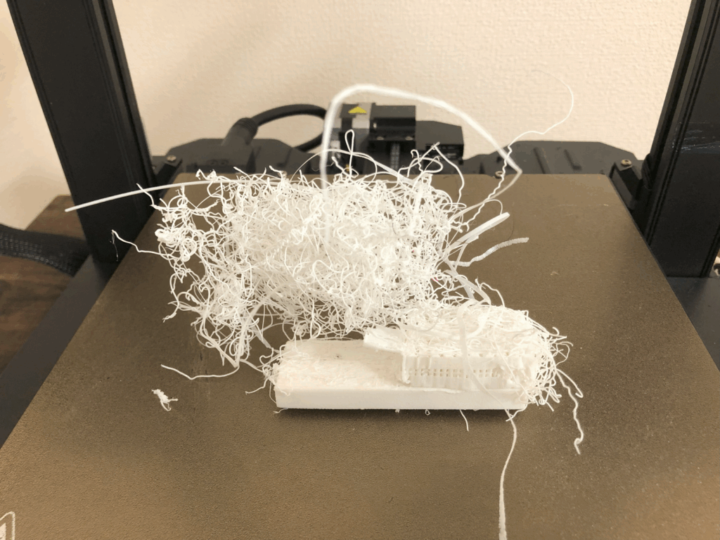 3Dプリンターの代表的な印刷失敗例。造形物の土台部分は四角く印刷されているが、その上でフィラメントが正常に積層されず、まるで鳥の巣のようにぐちゃぐちゃに絡み合った塊になっている。