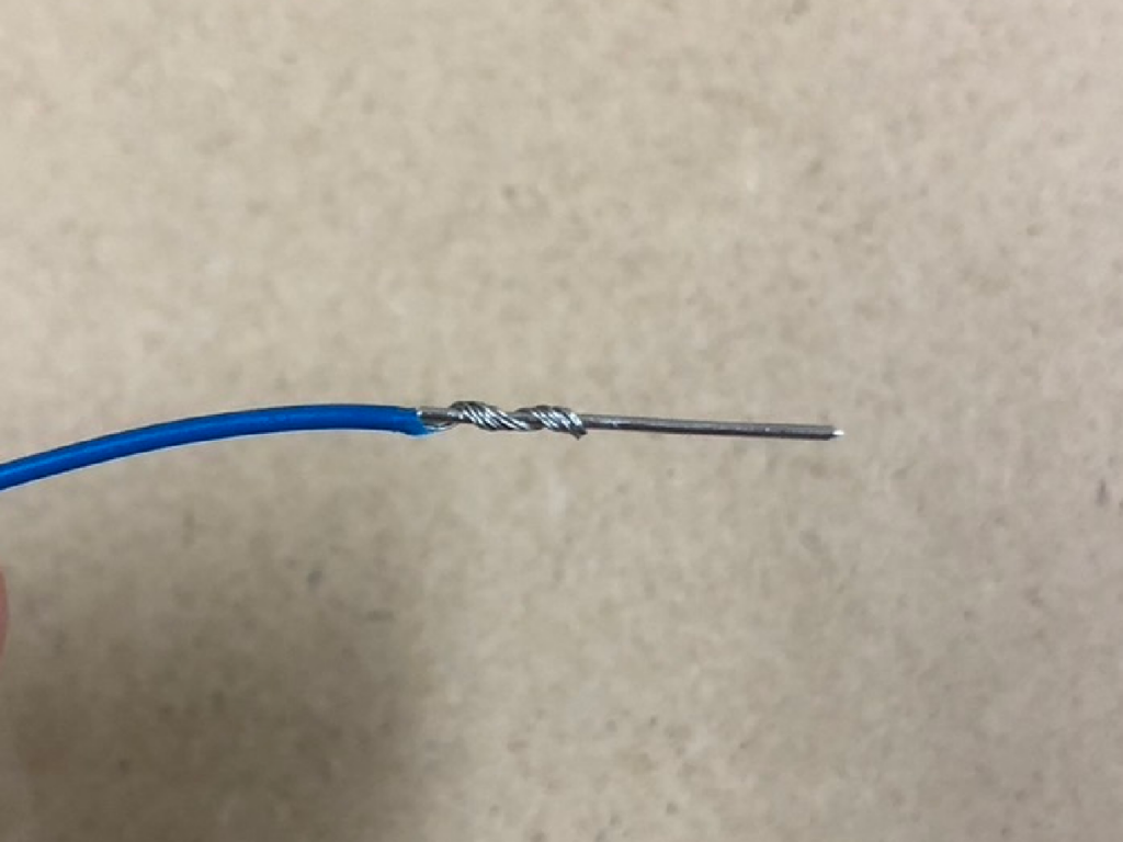 剥き出しにした電線の心線を、ピンとなる鈴メッキ線に巻き付けて固定している工程