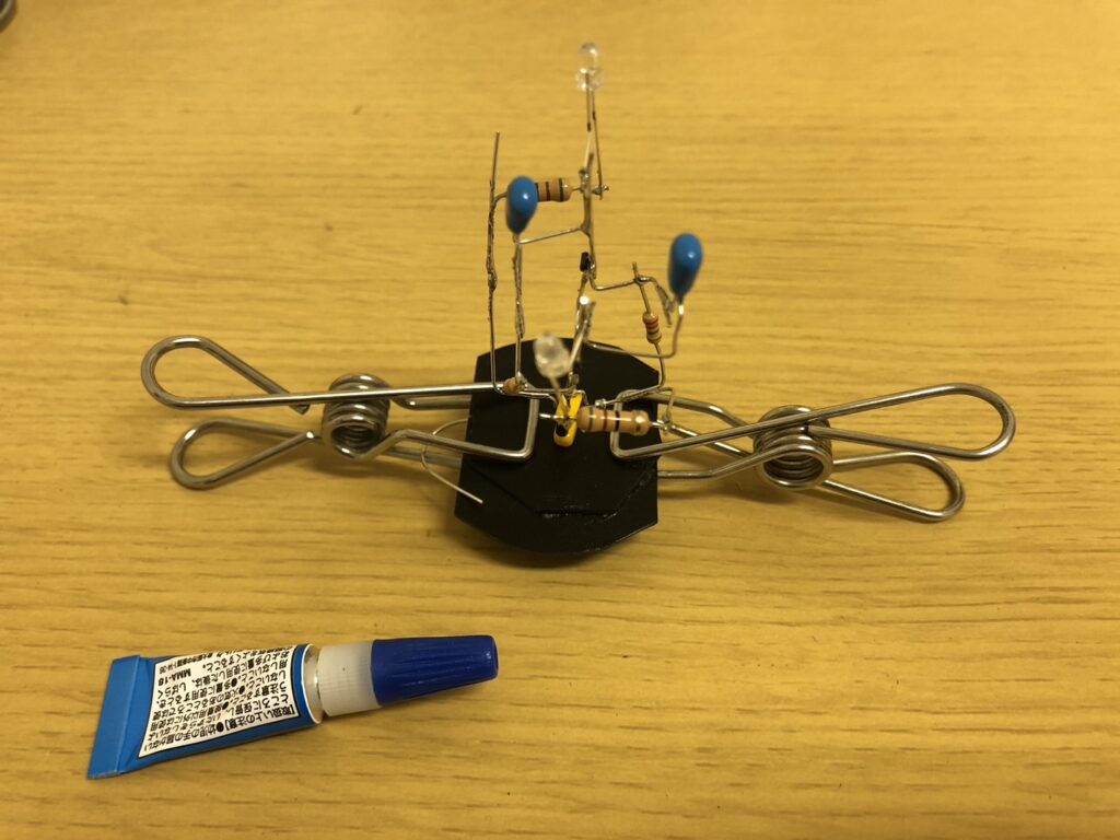 Astable multivibrator circuit being fixed to a plastic base plate with clamps during curing