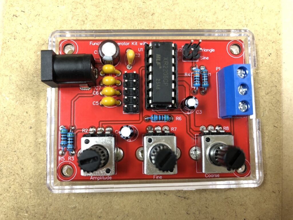 発振回路キットのすべての素子をはんだ付けした様子、抵抗とコンデンサ、ソケットなどが赤い基板上に配置されていることがわかる