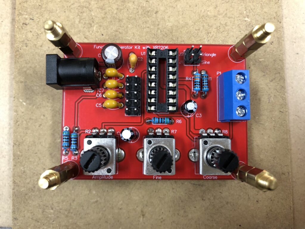 発振回路キットのすべての素子をはんだ付けした様子、抵抗とコンデンサ、ソケットなどが赤い基板上に配置されていることがわかる