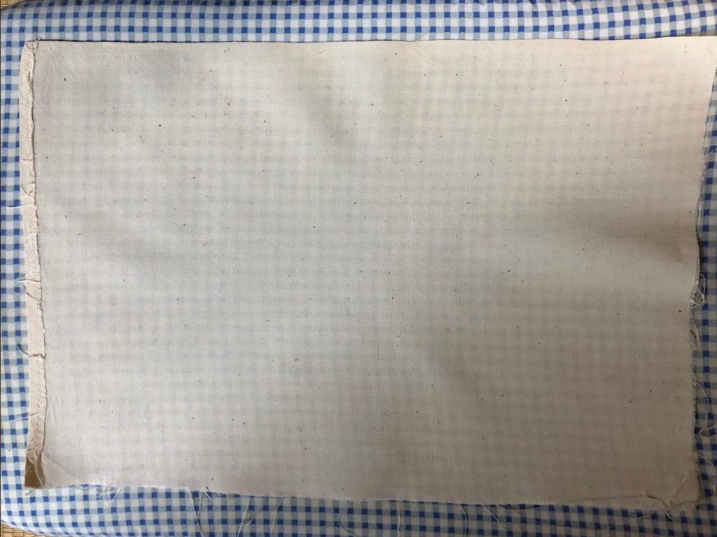水通しして乾かした布のシワをアイロンで伸ばしている様子。布を最も伸びた状態にして、木枠にタイトに張るための準備。アイロン後の布