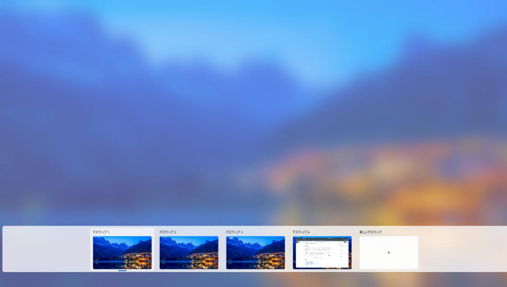 Windowsのデスクトップ切り替え画面です。左から「デスクトップ1」、「デスクトップ2」、「デスクトップ3」、「デスクトップ4」、「新しいデスクトップ」というタブが横一列に並んでいます。「デスクトップ1」~「デスクトップ3」は同じ山と湖の夜景の壁紙を表示しています。「デスクトップ4」はブラウザのウィンドウが開いています。右端には「新しいデスクトップ」を作成するためのプラスアイコンがあります。